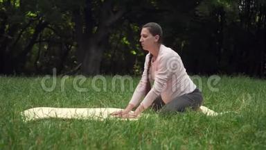 孕妇在公园的地毯上做瑜伽，做北极熊的姿势。